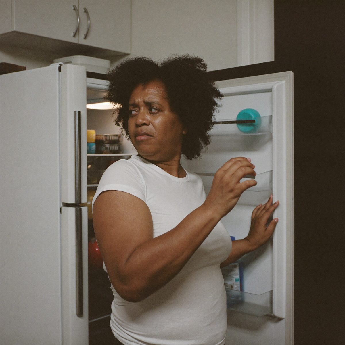Mulher desanimada sentada na cozinha à noite, diante de um prato sem graça